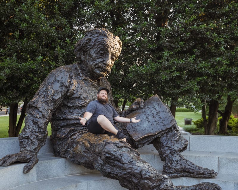 Someone sitting on the lap of the Albert Einstein Memorial